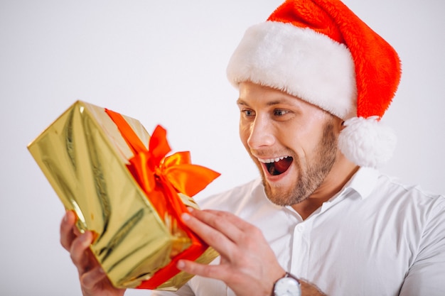 Portrait of man in santa hat holding christmas golden present box