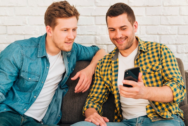 Portrait of a man showing something to his friend on smartphone