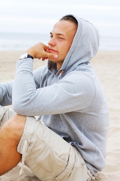 Portrait of man sitting on the beach and thinking