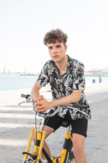 Free photo portrait of a man sitting on bicycle looking at camera