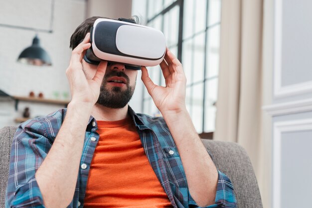 Portrait of a man sitting on sofa wearing virtual reality glasses