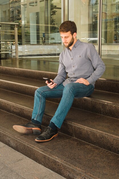 Portrait of a man sitting on staircase using smartphone