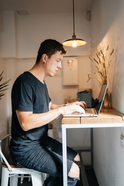 Portrait of man sitting at a table at home working on a laptop.