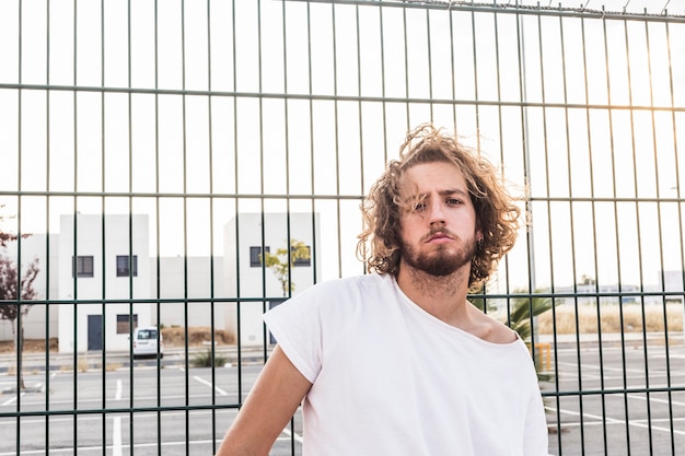 Free photo portrait of a man standing in front of fence