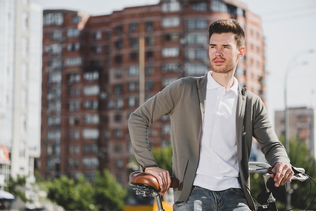 Portrait of man standing with bicycle in the city