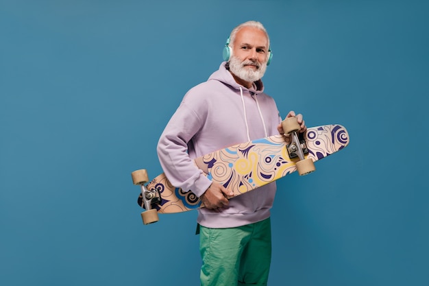 Free photo portrait of man in stylish hoodie holding skate board