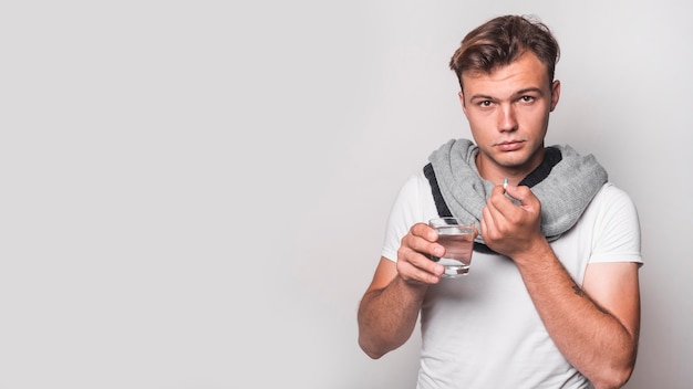 Portrait of a man taking capsule with water on white background