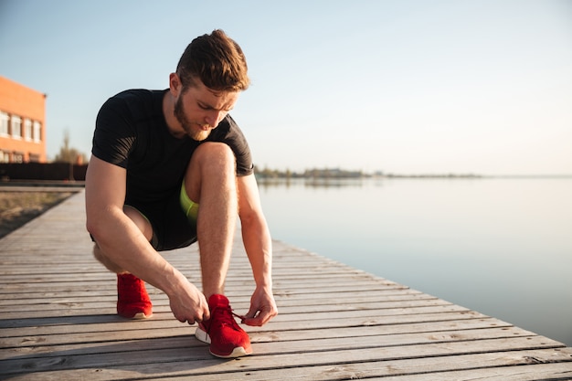 Ritratto di un uomo che lega i lacci delle scarpe sulla scarpa sportiva