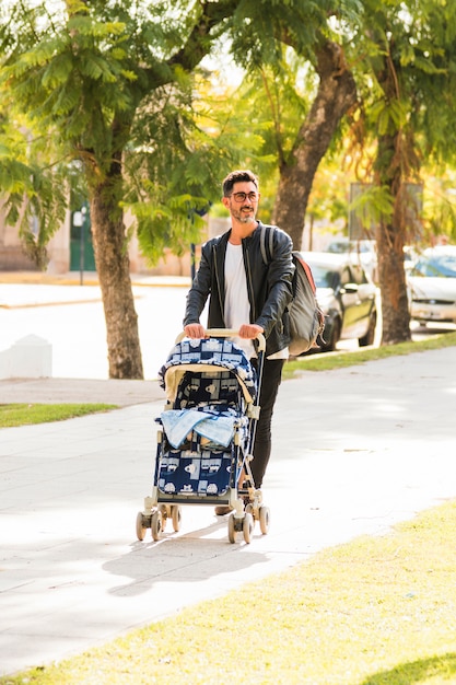 Portrait of a man walking with baby carriage on the city street