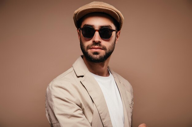 Портрет мужчины в бежевой кепке и солнцезащитных очках на изолированном фоне