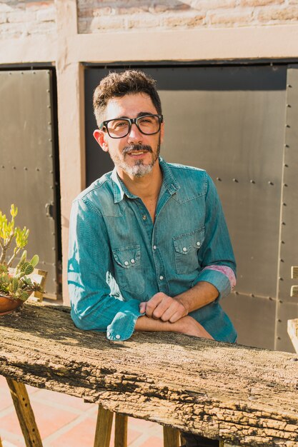 Portrait of a man wearing eyeglasses leaning on an outdoor table