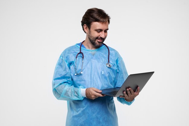 Portrait of man wearing medical gown and holding laptop
