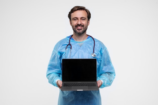 Portrait of man wearing medical gown and holding laptop