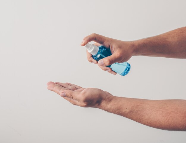 Portrait of a man at white background sanitizing his hand  