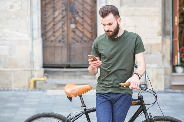 Portrait of a man with bicycle standing on cellphone