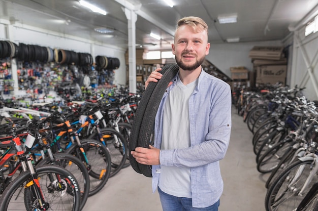 Портрет мужчины с велосипедными шинами в магазине