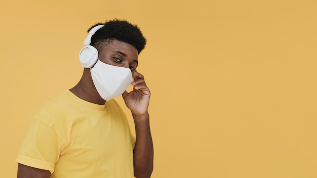 Free photo portrait of man with face mask and headphones with copy space