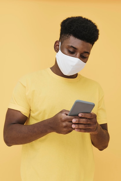 Free photo portrait of man with face mask holding smartphone