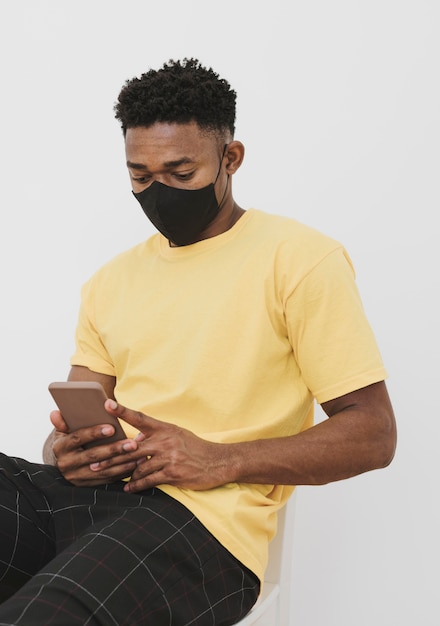 Портрет мужчины с маской для лица и смартфоном