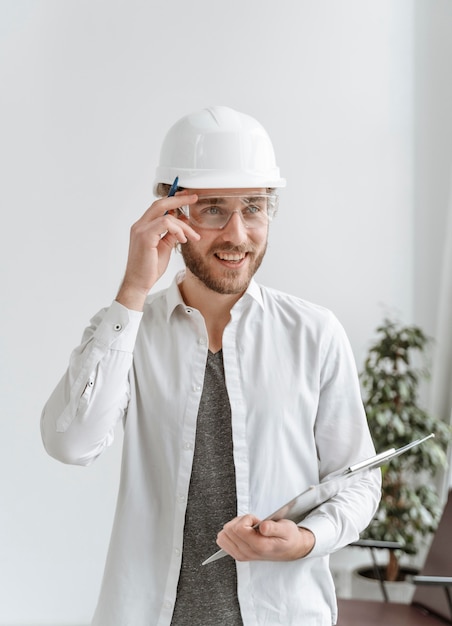 Foto gratuita uomo del ritratto con il casco in ufficio