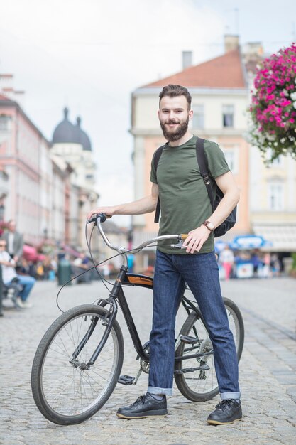 Портрет человека с его велосипедом, глядя на камеру