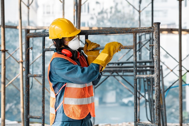 Portrait man with safety equipment side view carrying ladder