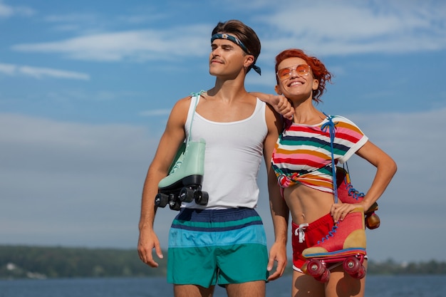Portrait of man and woman at the beach with roller skates in 80's aesthetic