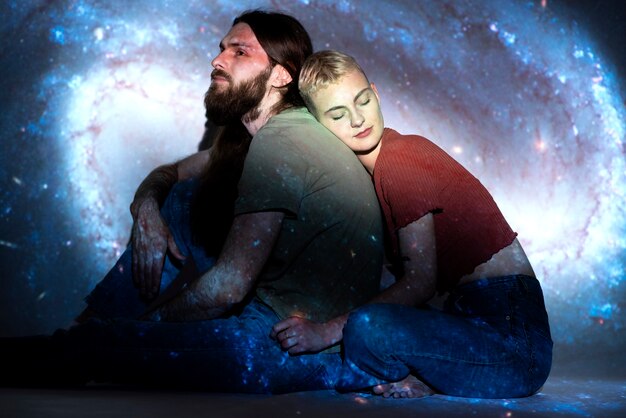 Portrait of man and woman posing with universe projection texture