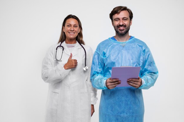 Portrait of man and woman wearing medical gown and holding clipboard