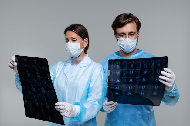 Free photo portrait of man and woman wearing medical gowns and holding ct scan