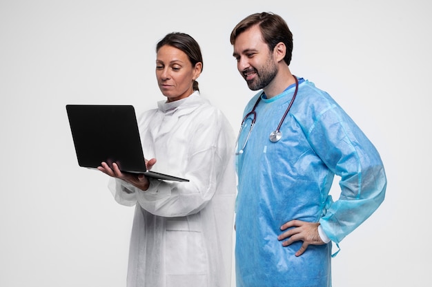 Portrait of man and woman wearing medical gowns and holding laptop