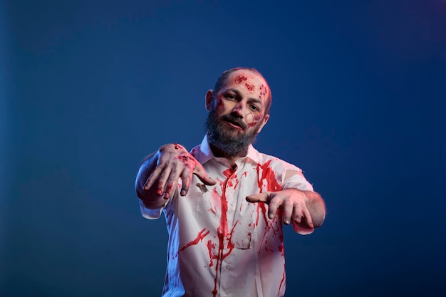 Portrait of man zombie with scratches and sinister wounds posing in front of camera, dangerous undead corpse with scary scars and creepy face in studio. Doomsday cruel monster devil.