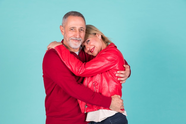 Portrait of mature couple standing against turquoise background