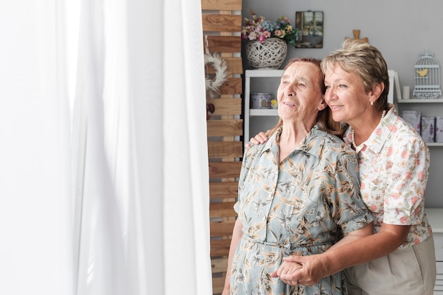 Portrait of mature daughter with her senior mother at home