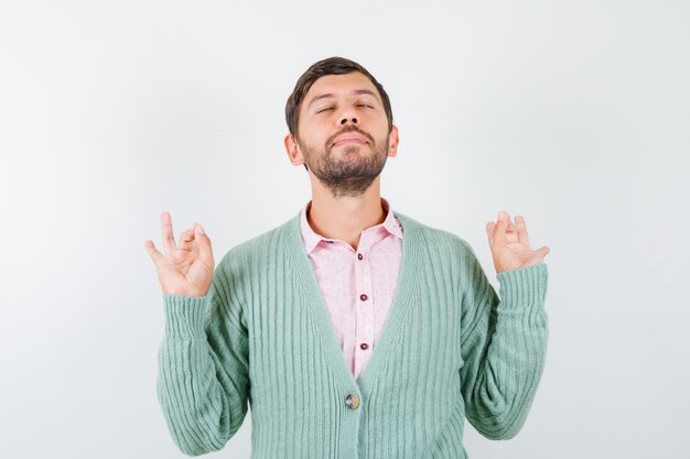 Portrait of mature man showing ok gesture in shirt, cardigan and looking focused front view