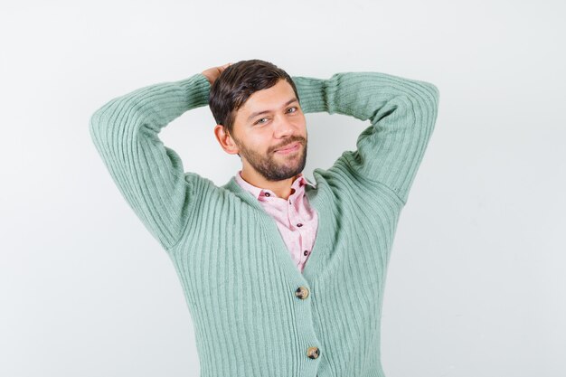 Portrait of mature man with hands behind head while posing in shirt, cardigan and looking happy front view