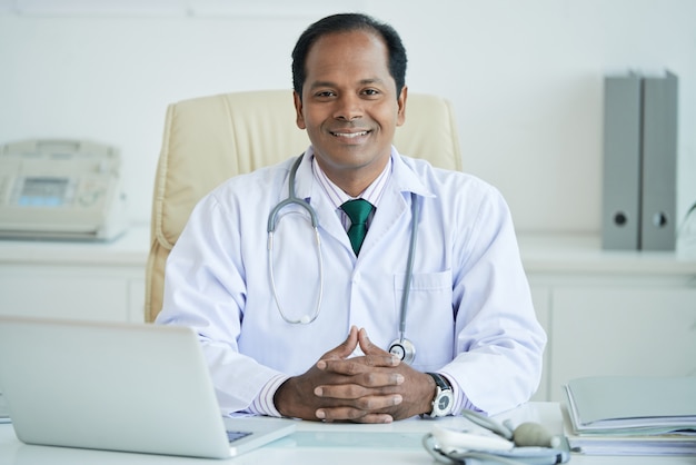 Portrait Of Mature Therapist Sitting At Table looking At Camera