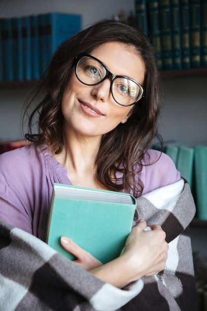 Free photo portrait of a mature woman covered in blanket holding book