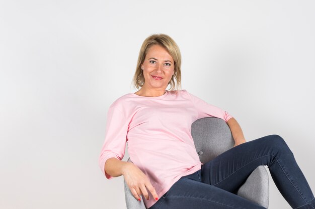 Portrait of mature woman relaxing on gray chair against white background