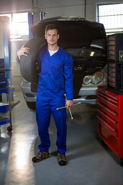 portrait of mechanic holding tyre and lung wrench