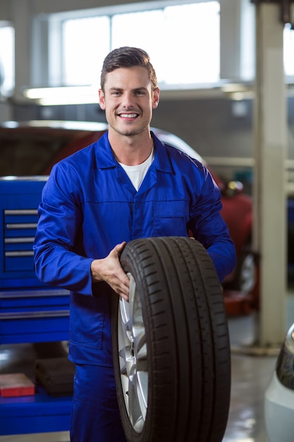 Portrait of mechanic holding a tyre