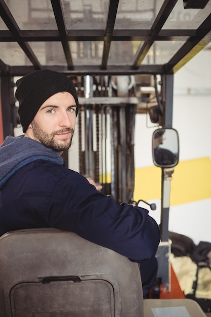 Free photo portrait of mechanic sitting on forklift