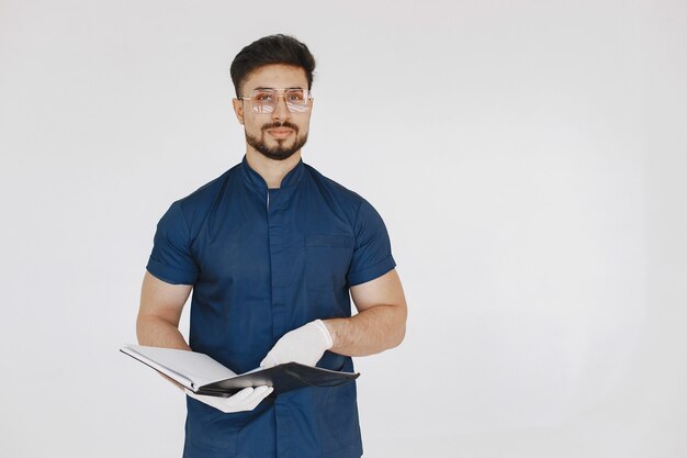 A portrait of a medical doctor posing against white wall