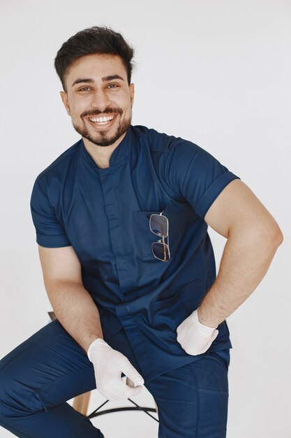 A portrait of a medical doctor posing against white wall