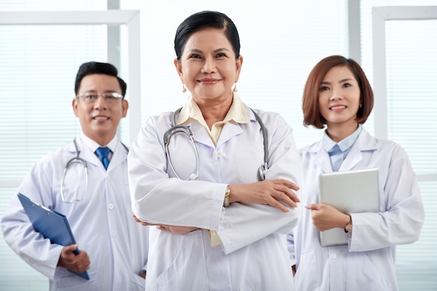 Portrait of medical team of three standing in the hospital looking at camera