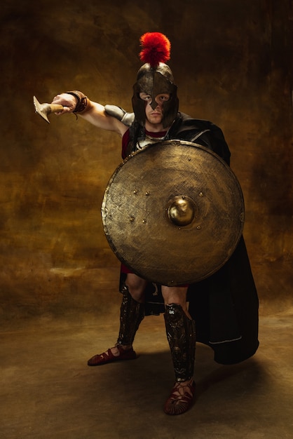 Portrait of medieval person warrior in war equipment isolated on vintage dark