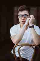 Free photo portrait of men sitting on chair with white t-shirt and sunglasses in the street