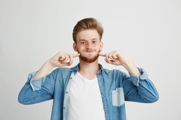 Portrait of merry cheerful young guy making funny face fooling.