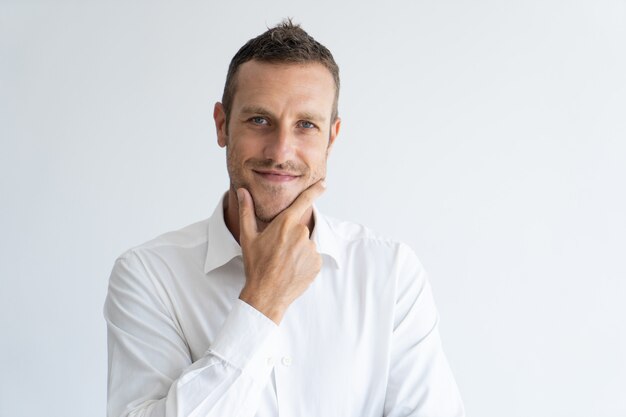 Portrait of mid adult businessman with interested expression touching his chin