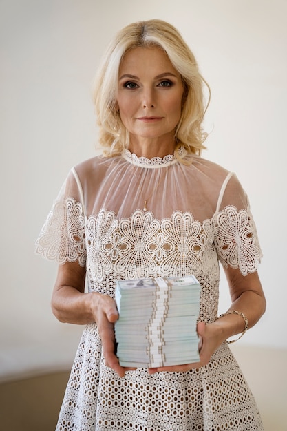 Free photo portrait of middle-aged blonde rich woman with banknotes